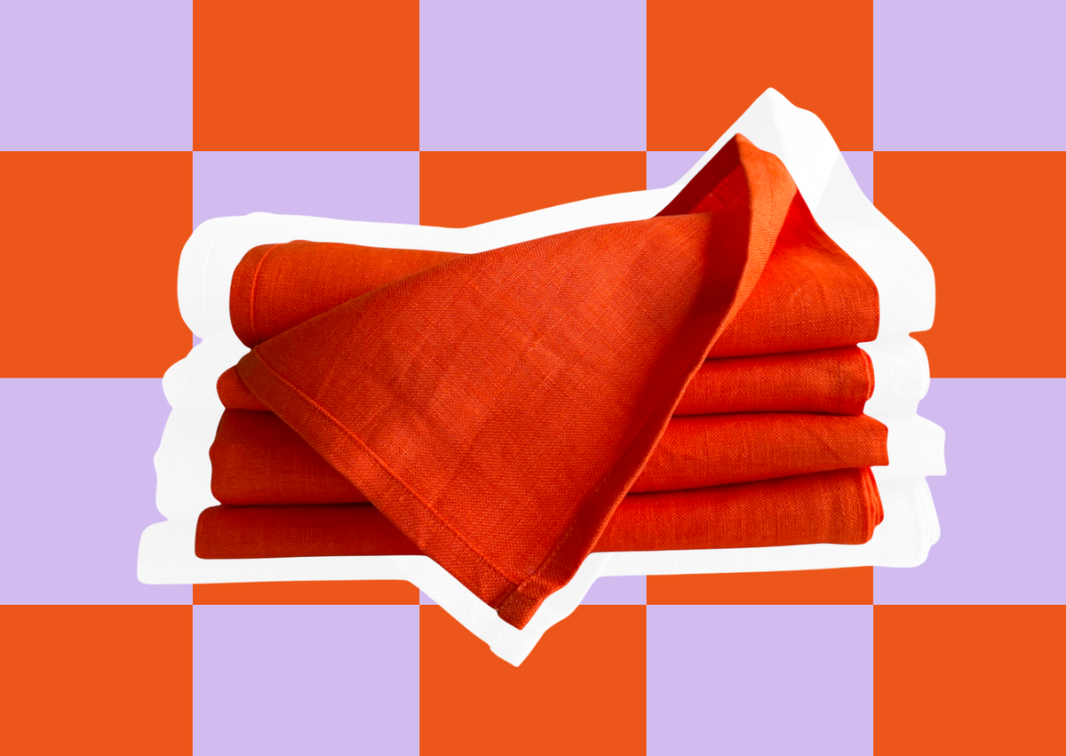 Stack of Spanish Orange linen napkins on a purple and orange checkerboard
